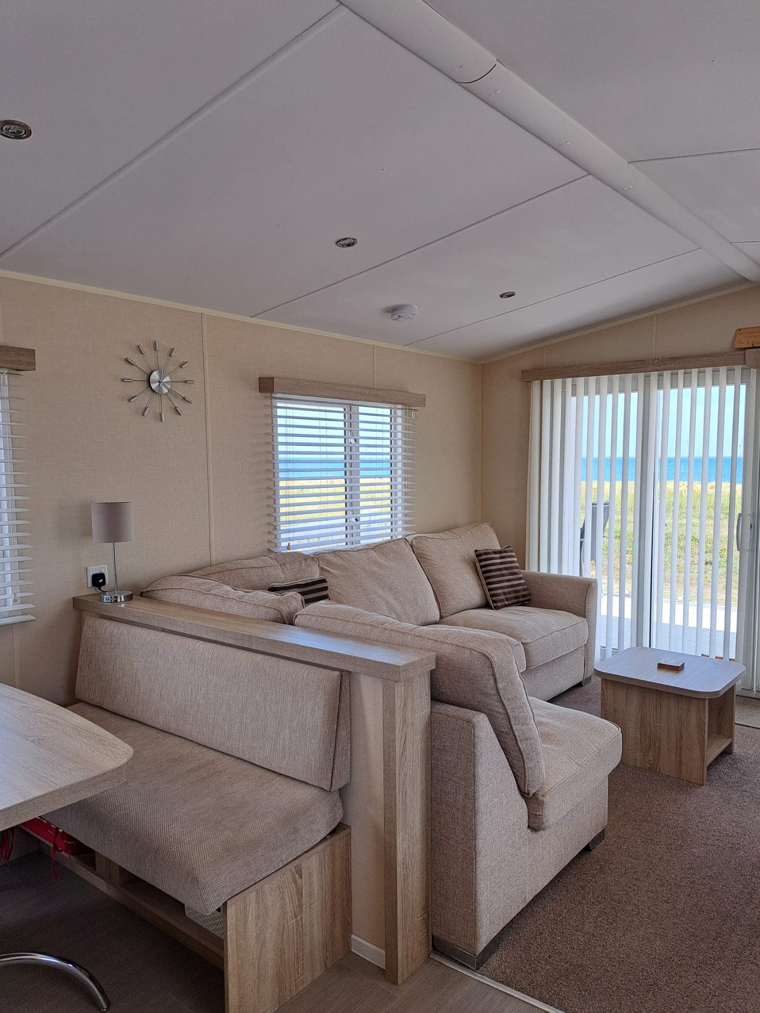 Lounge with the large sofa and dining bench, windows looking out to the coast
